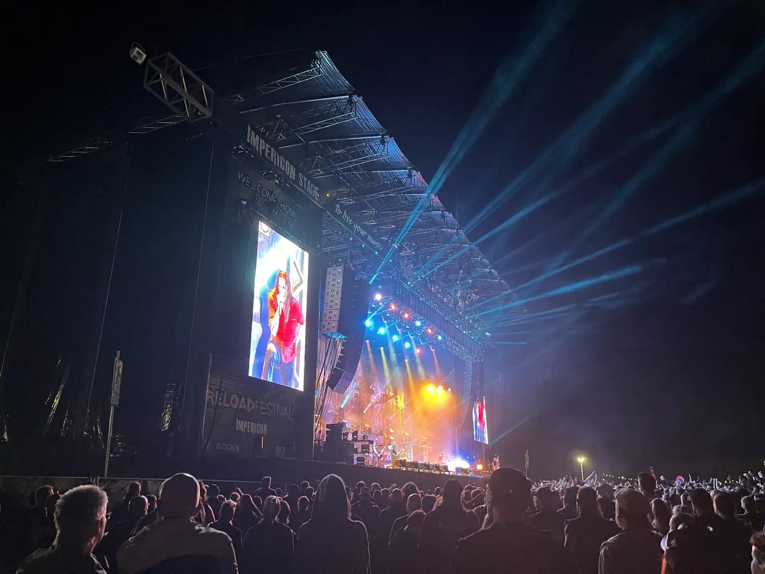 Open-air stage with an audience, lighting show and a side LED wall for live video