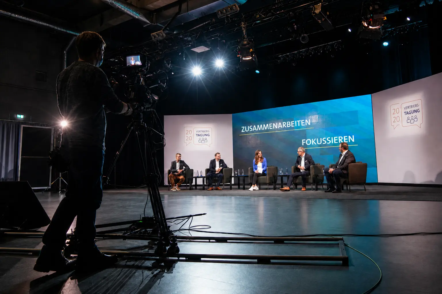 Studio4x camera operator with a studio camera on tracks in front of a panel discussion at a corporate event