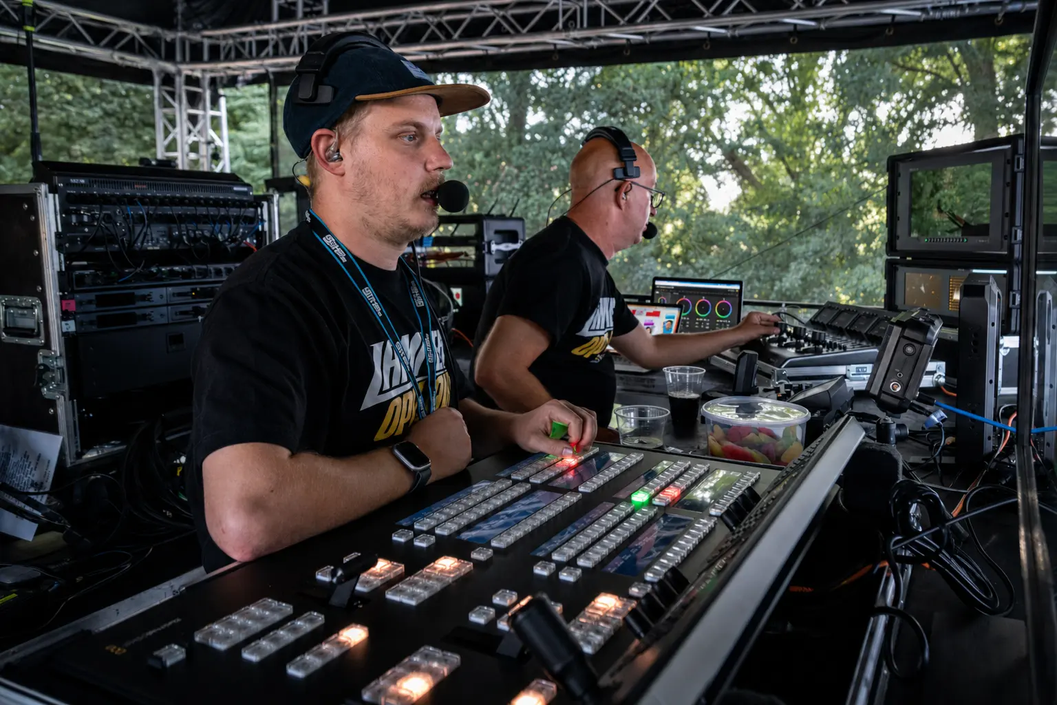 Two Studio4x crew members wearing headsets at a vision mixer, audio desk and monitors during an on-location production